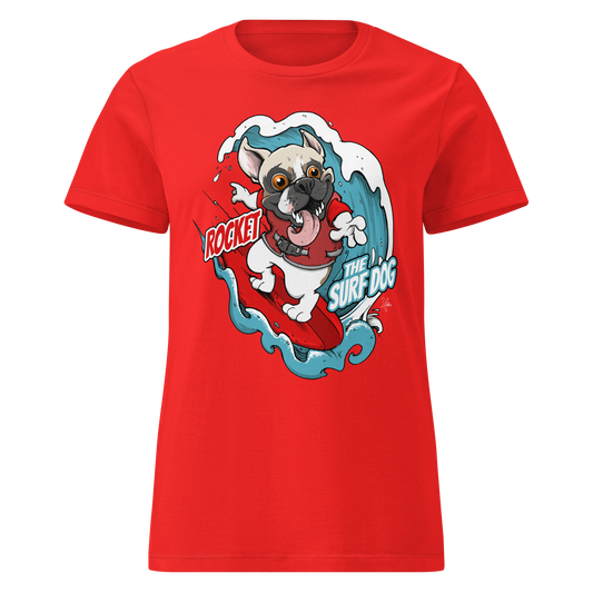 A bright red short-sleeve crewneck t-shirt featuring a cartoon graphic of a white French Bulldog surfing on a red board with blue waves, accompanied by the text 'ROCKET THE SURF DOG'.