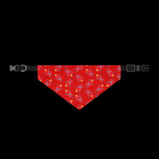 A red pet bandana with a repeating pattern of colorful rockets, shown flat with black plastic buckles on both ends.