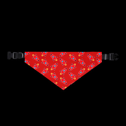 A red pet bandana with a repeating pattern of colorful rockets, shown flat with black plastic buckles on both ends.