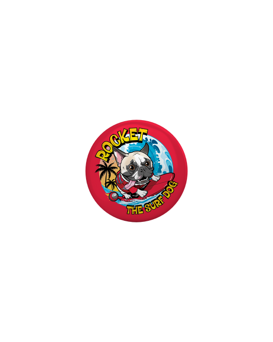 A round red button badge featuring a colorful cartoon illustration of a French Bulldog on a surfboard with the text 'ROCKET THE SURF DOG.'