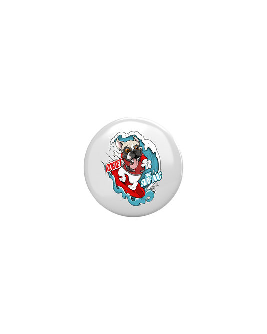 A round white button badge featuring a colorful cartoon illustration of a French Bulldog on a surfboard with the text 'ROCKET THE SURF DOG.'
