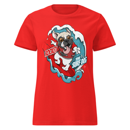 A bright red short-sleeve crewneck t-shirt featuring a cartoon graphic of a white French Bulldog surfing on a red board with blue waves, accompanied by the text 'ROCKET THE SURF DOG'.